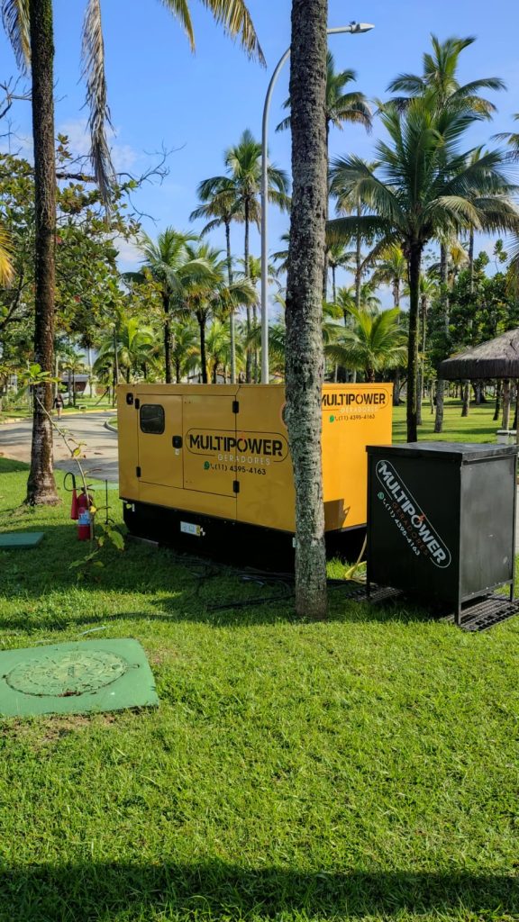 Gerador amarelo em área verde com palmeiras.