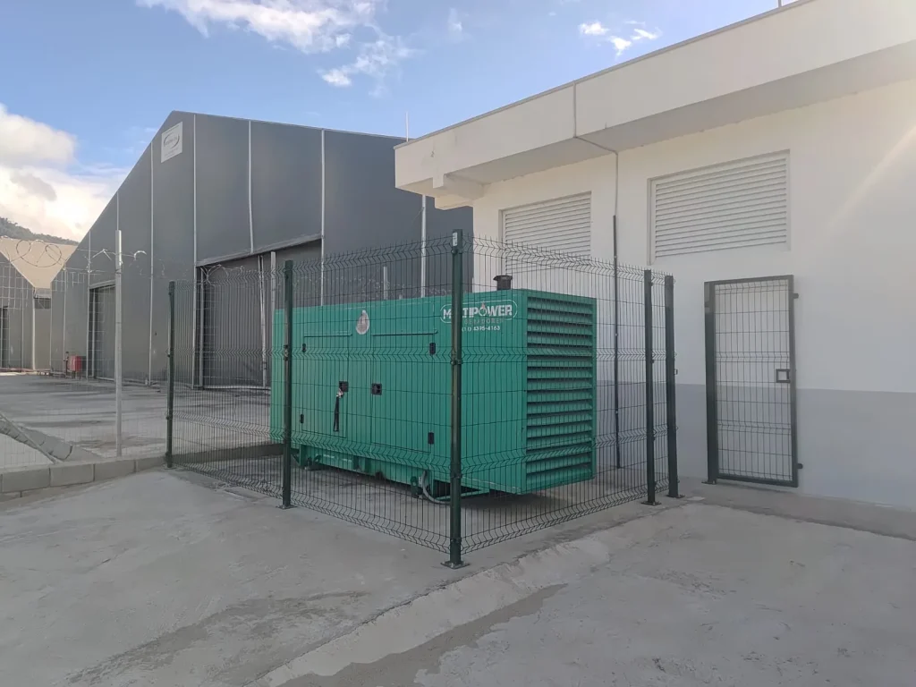 Gerador verde instalado em área cercada junto a edificação.